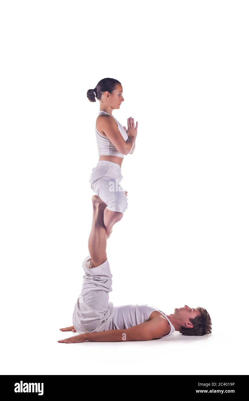 Pareja practicando yoga acro contra fondo blanco Foto de stock