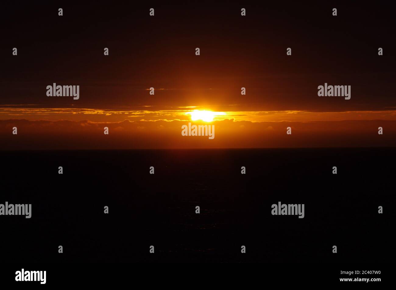 Secuencia de imágenes de una puesta de sol desde el mismo punto de vista puesta de sol naranja profundo, el sol naranja oscuro emerge de la nube oscura al mar oscuro, puesta de sol amarilla sobre el s Foto de stock