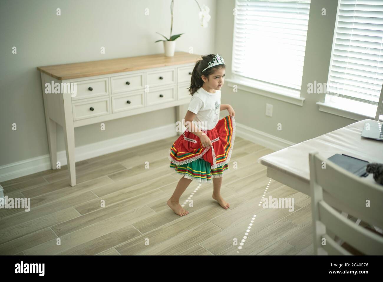 Chica disfruta de una clase de baile en línea con un ordenador portátil conectado a una televisión en casa Foto de stock
