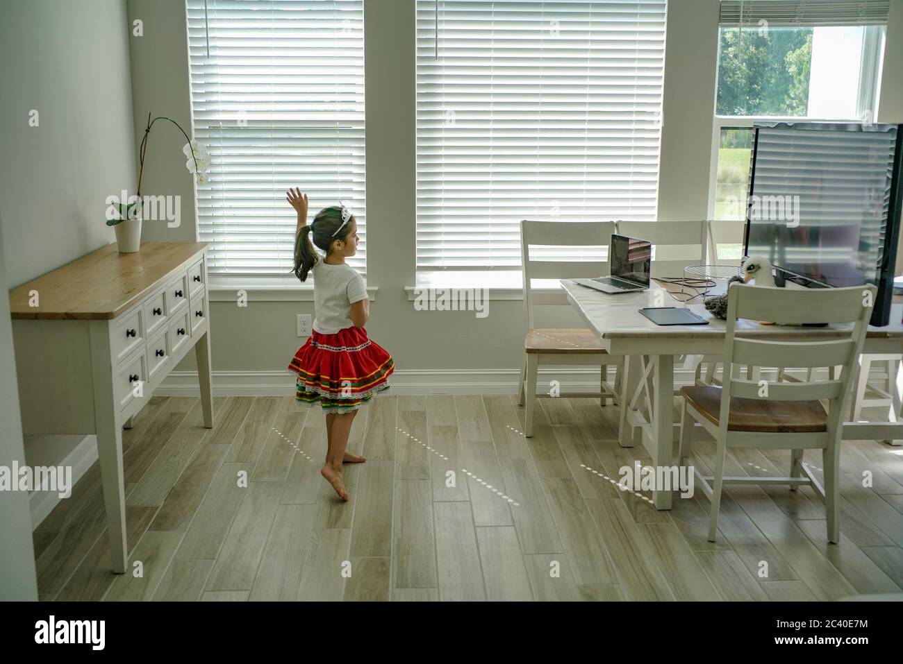 Chica disfruta de una clase de baile en línea con un ordenador portátil conectado a una televisión en casa Foto de stock
