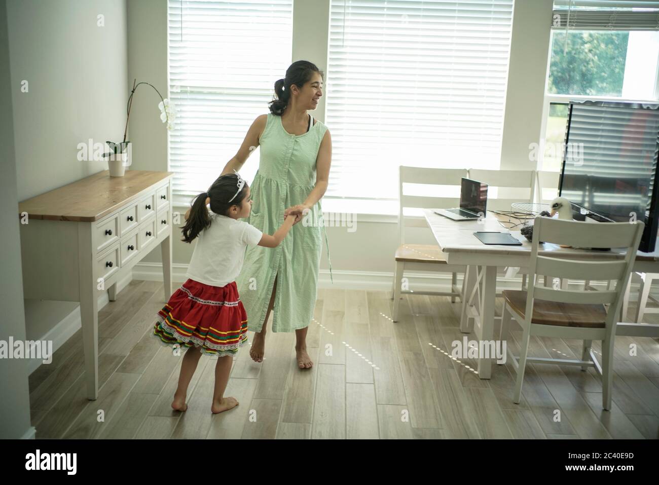 Chica disfruta de una clase de baile en línea con un ordenador portátil conectado a una televisión en casa Foto de stock