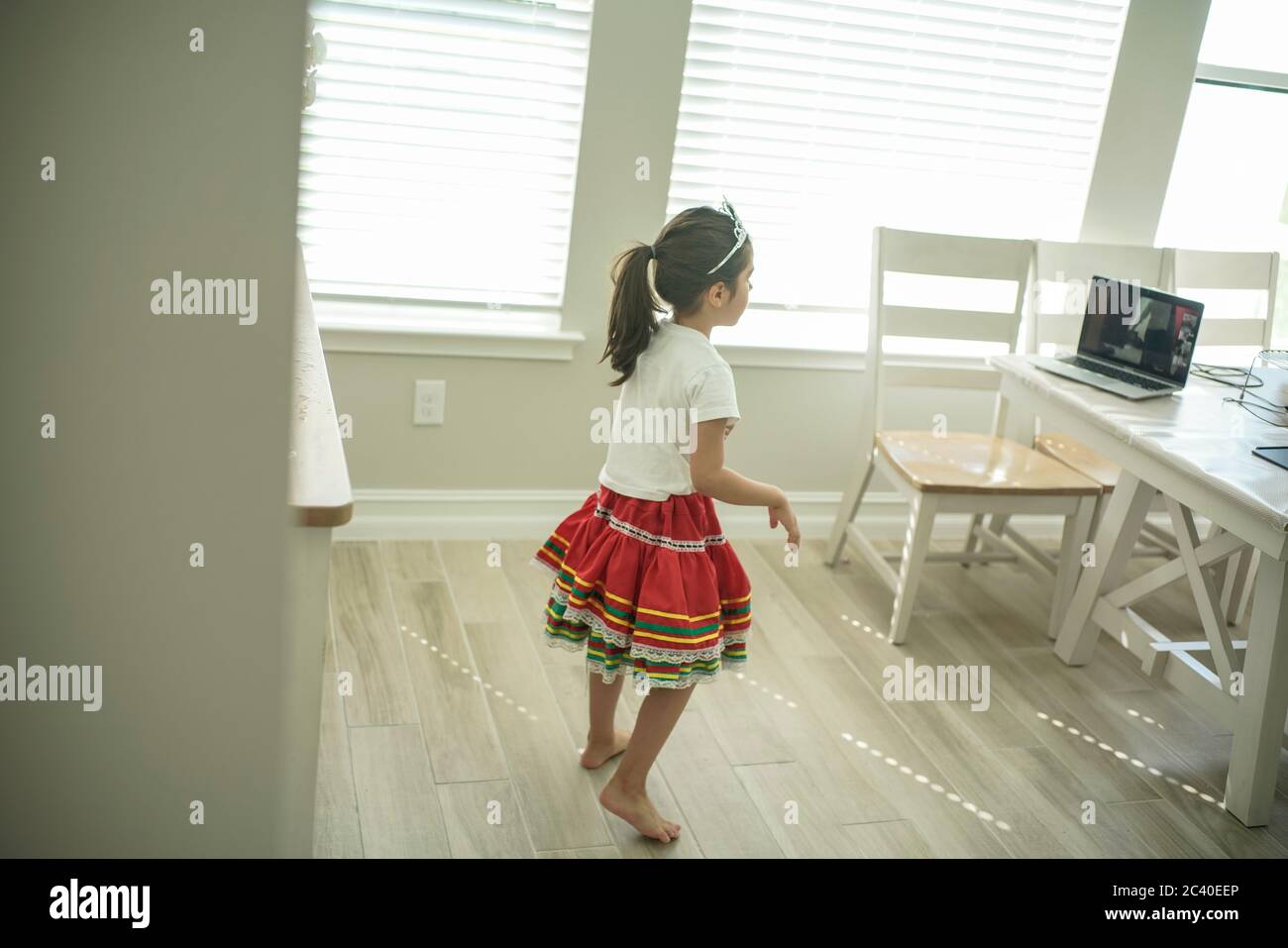 Chica disfruta de una clase de baile en línea con un ordenador portátil conectado a una televisión en casa Foto de stock