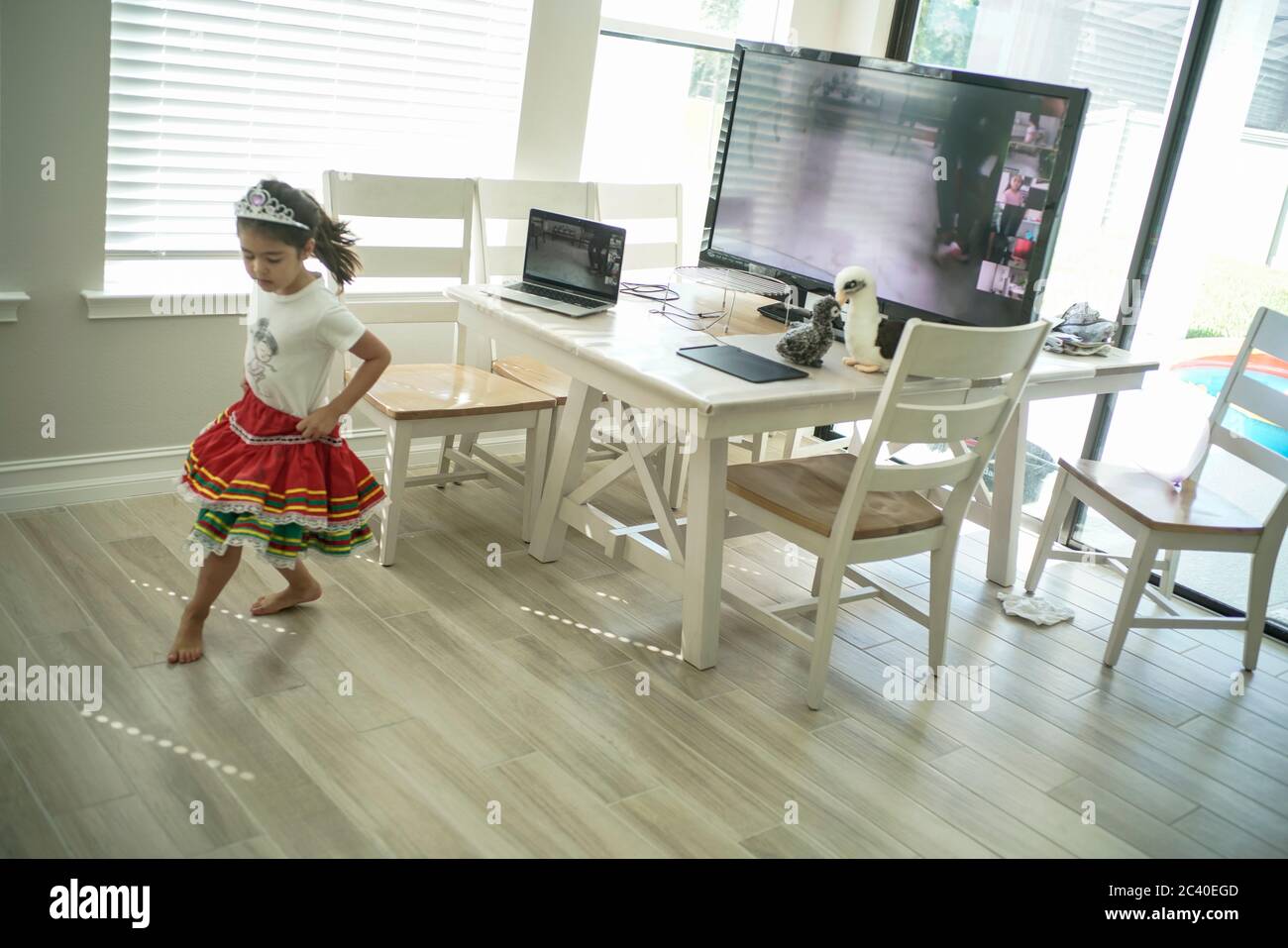 Chica disfruta de una clase de baile en línea con un ordenador portátil conectado a una televisión en casa Foto de stock