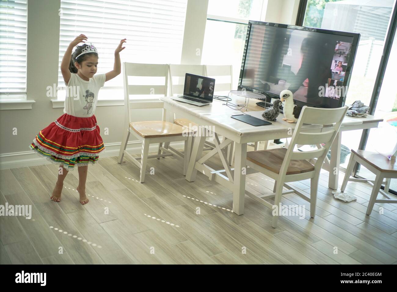 Chica disfruta de una clase de baile en línea con un ordenador portátil conectado a una televisión en casa Foto de stock