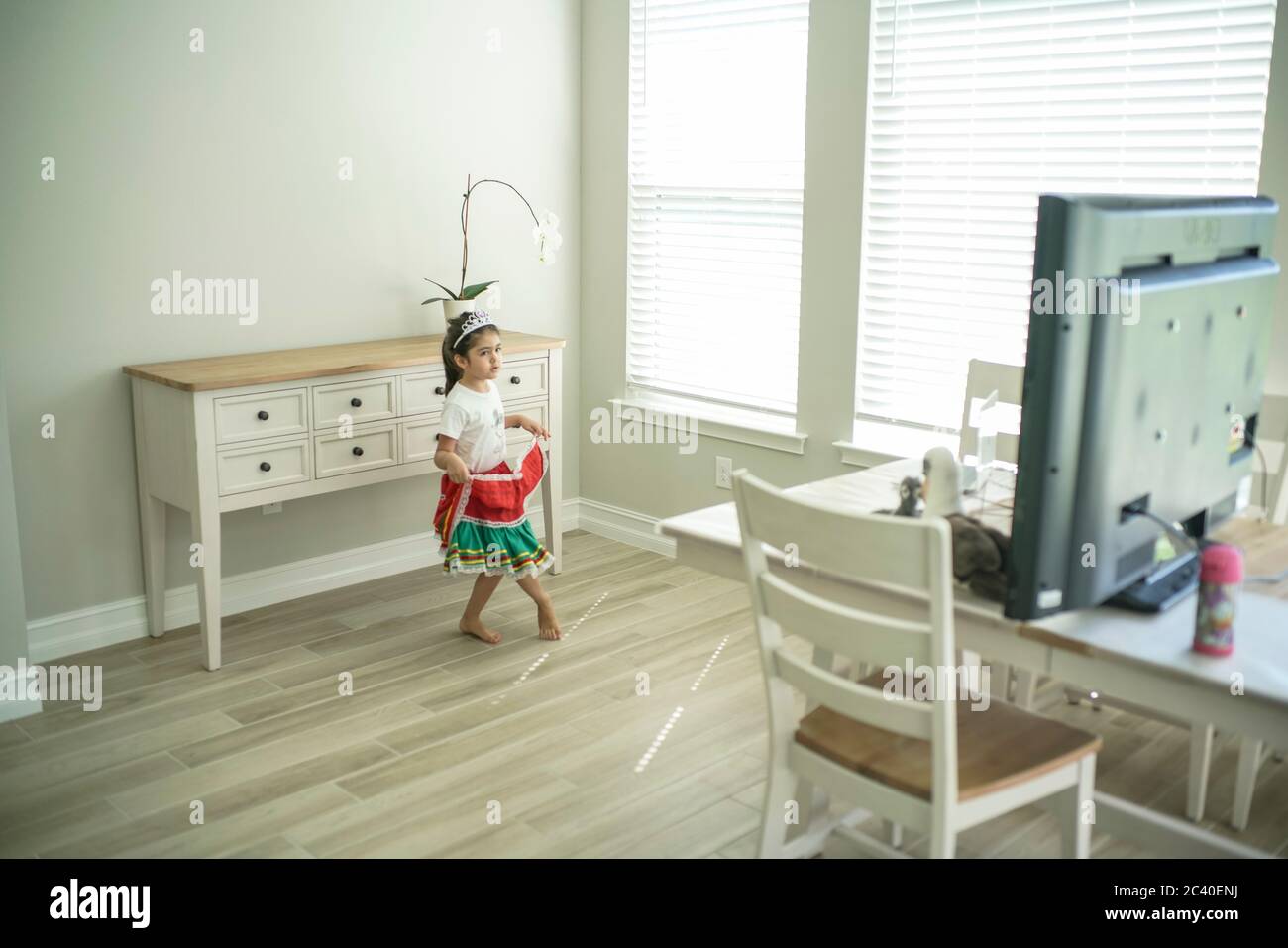 Chica disfruta de una clase de baile en línea con un ordenador portátil conectado a una televisión en casa Foto de stock