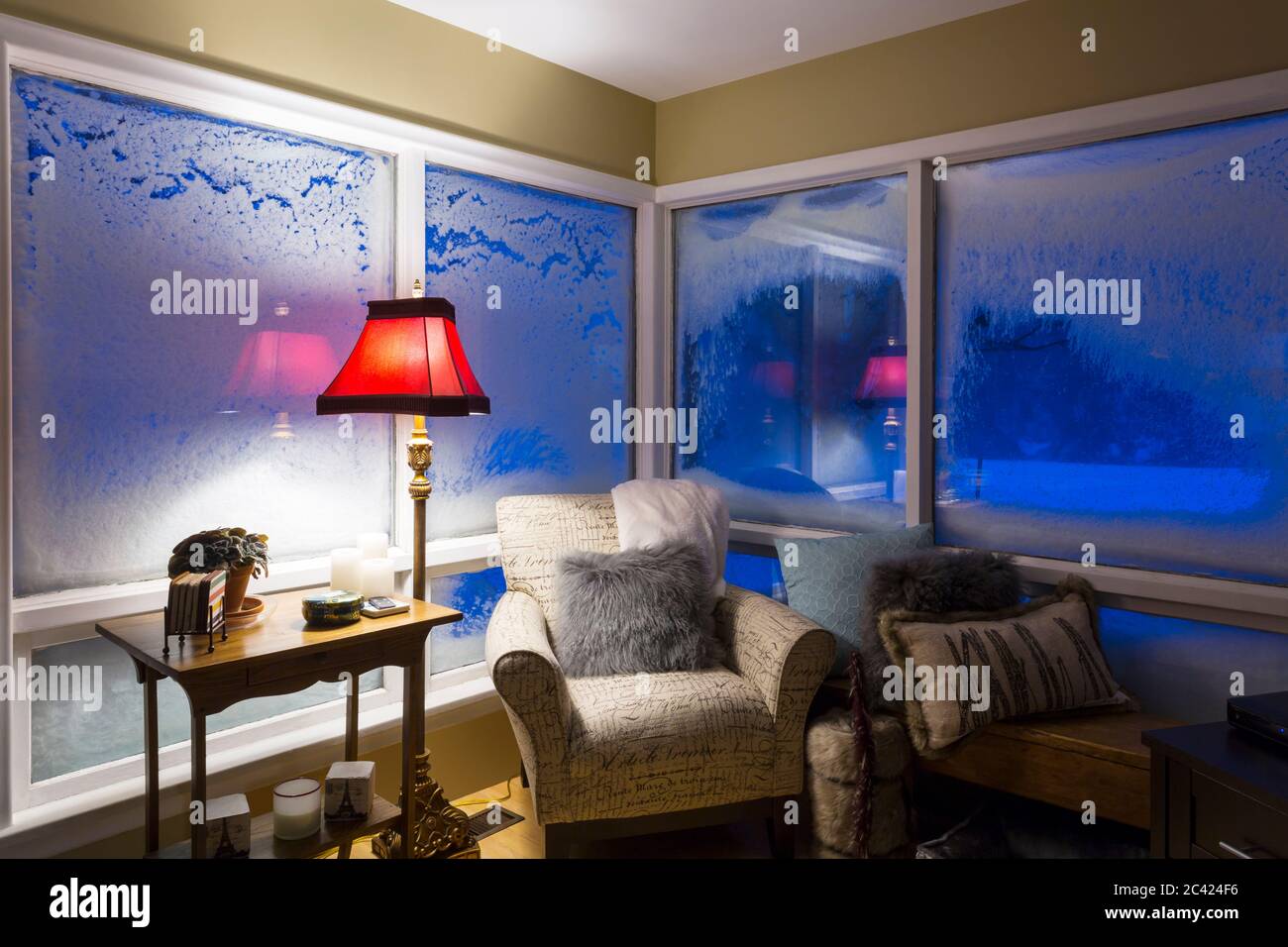 la sala de estar está cubierta con ventanas cubiertas de nieve por la noche durante la ventisca Foto de stock