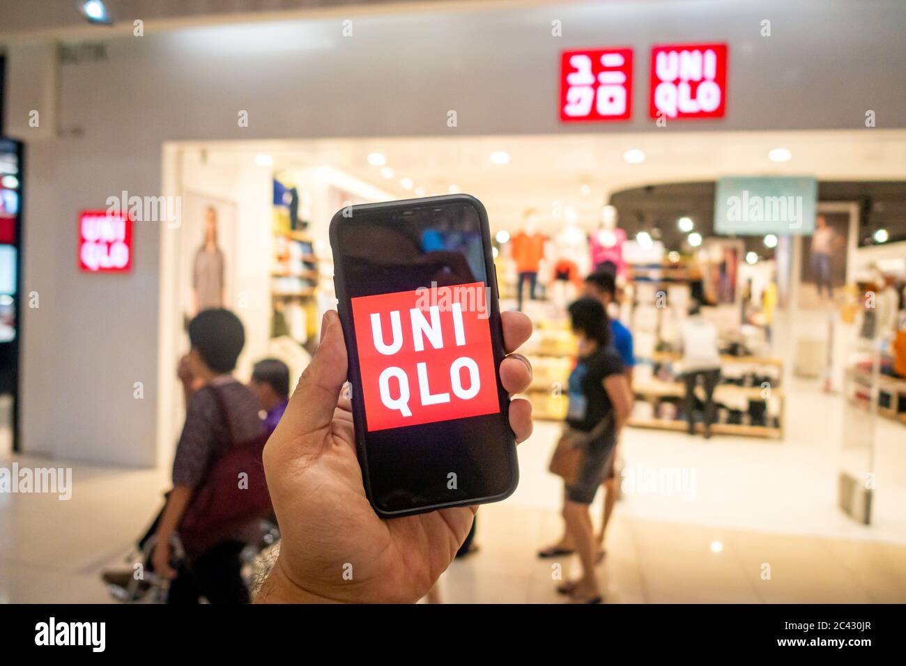 Un hombre sosteniendo una X iphone con las aplicaciones uniqlo delante de  la tienda Uniqlo. Uniqlo Apps es perfecto para aquellos que prefieren las  compras en línea Fotografía de stock - Alamy