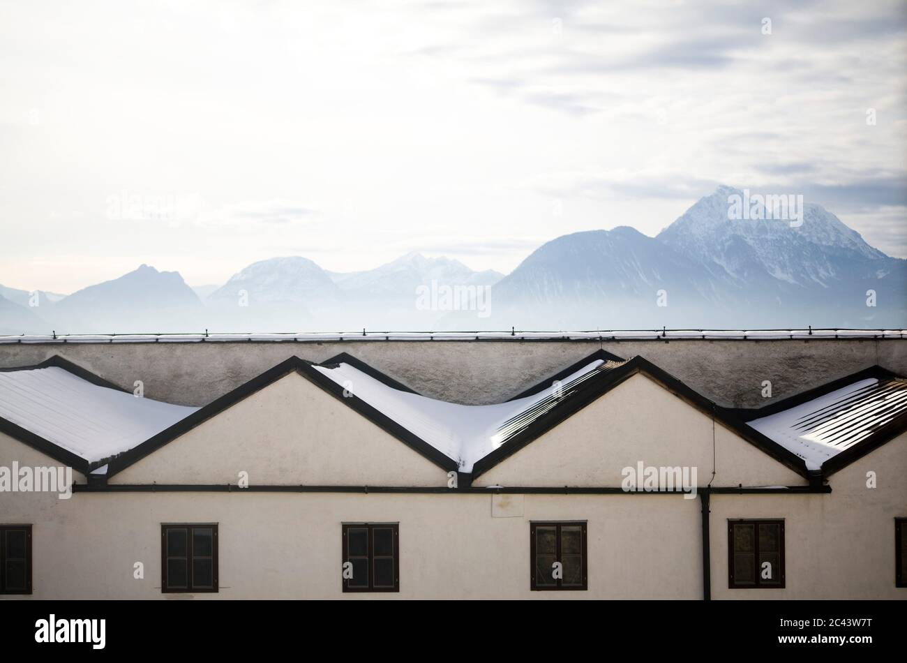 Alpes detrás de los tejados cubiertos de nieve, Salzburgo, Austria Foto de stock