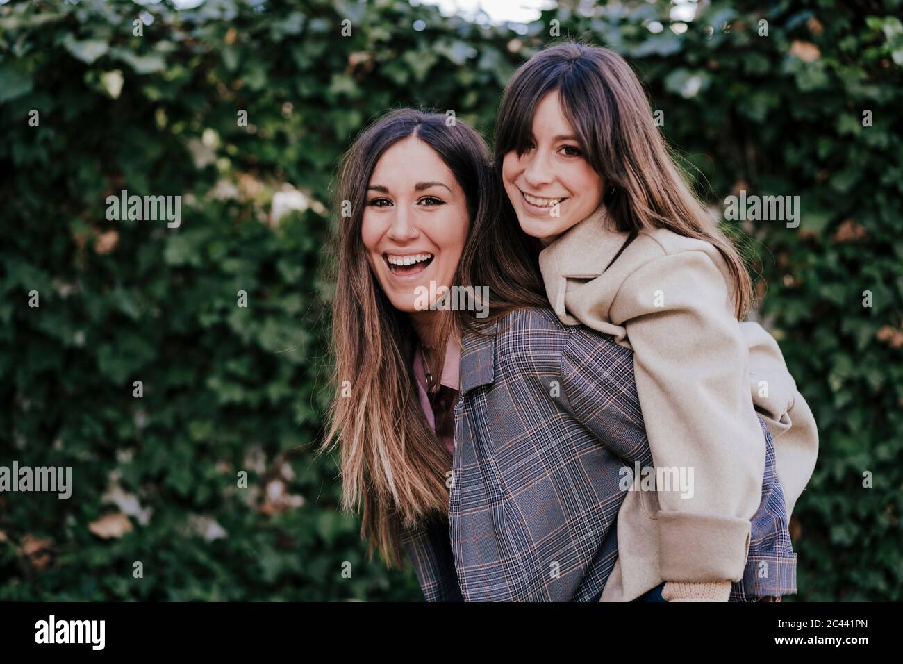 Poertrait de la mujer riendo dando a su amiga un paseo en piggyback Foto de stock