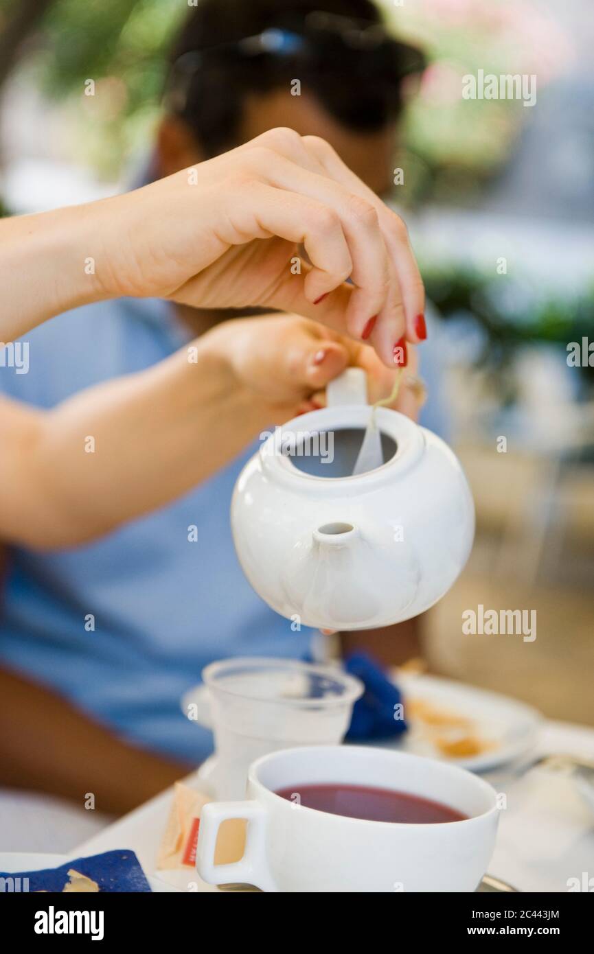 La mujer vierte el té en una taza Foto de stock