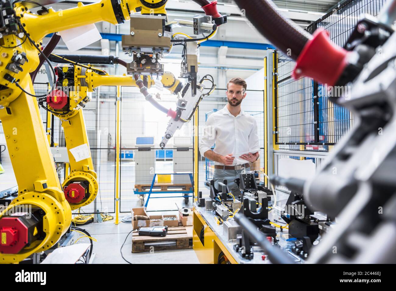 Experto en robótica segura que mira la maquinaria en la fábrica de fabricación Foto de stock