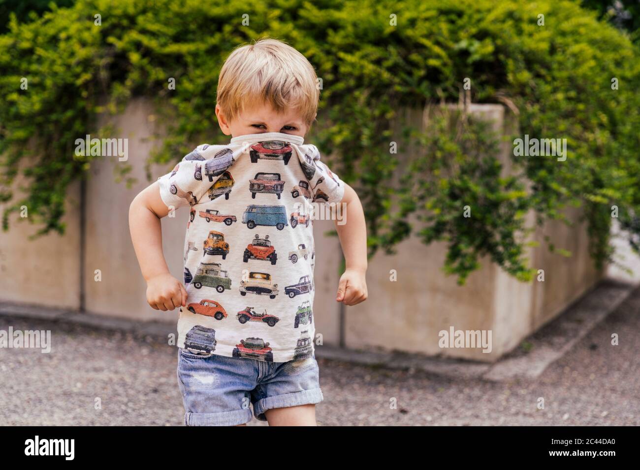 Retrato de niño cubriendo su boca y nariz con camiseta Foto de stock