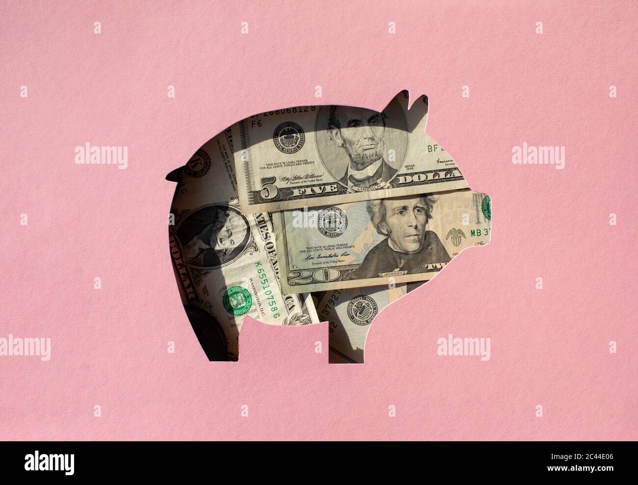 Agujero en forma de cerdo lleno de billetes en dólares Foto de stock