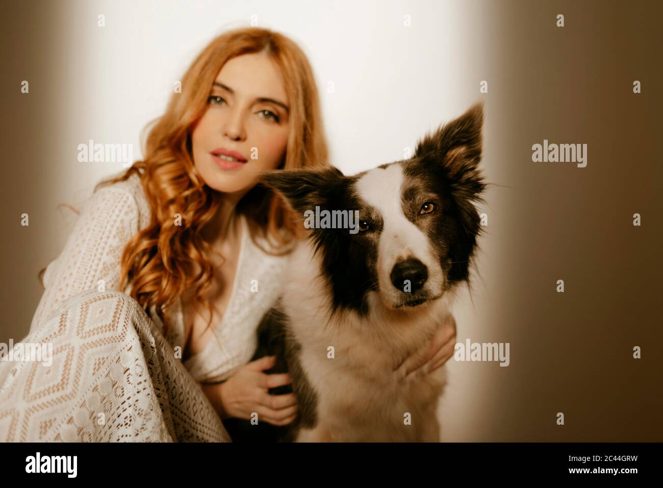 Mujer rubia en casa en pijama con un perro collie de frontera Foto de stock