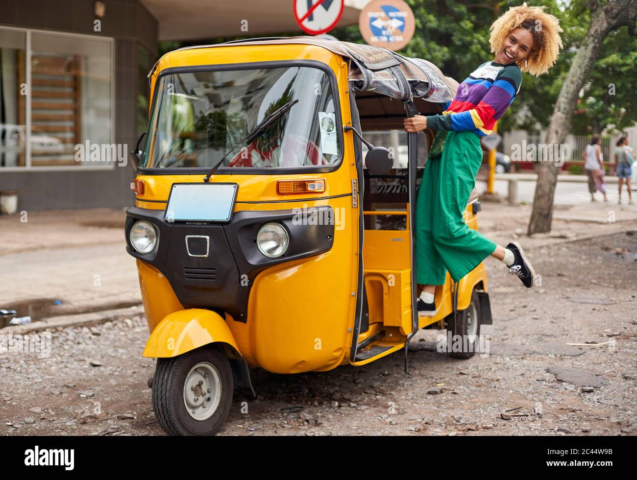 Alegre joven de pie en rickshaw en la ciudad Foto de stock