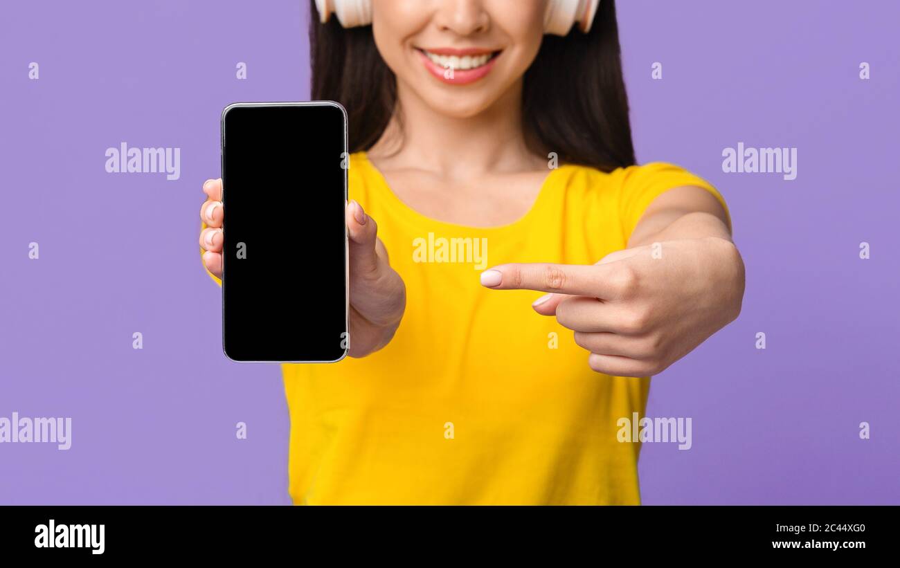 Descargar música en línea. Chica irreconocible en auriculares apuntando a  la pantalla negra del smartphone Fotografía de stock - Alamy