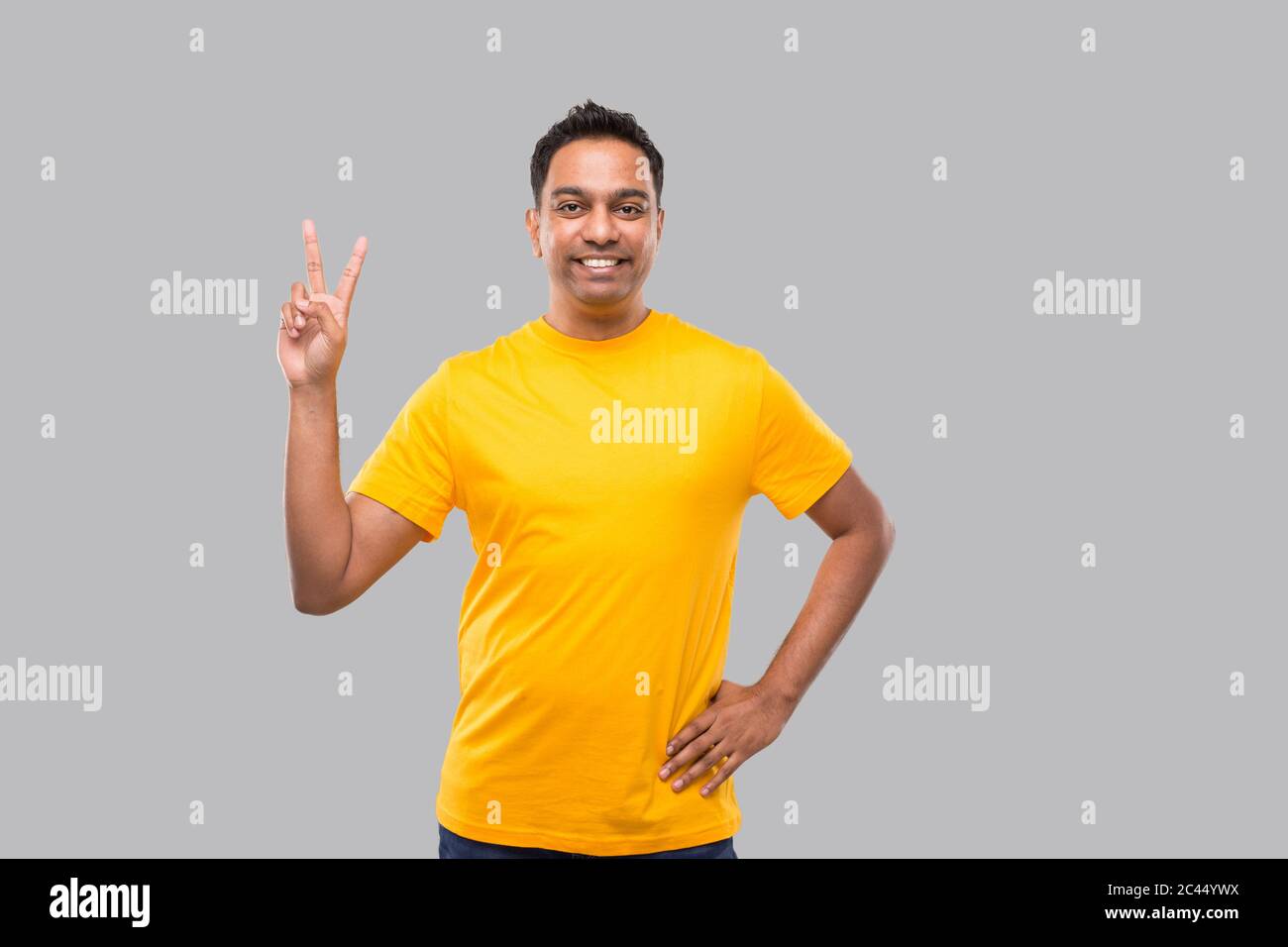 Hombre indio mostrando la señal de Paz aislado sonriendo Foto de stock