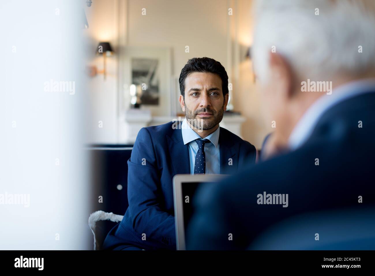 Dos hombres de negocios sentados en el interior, hablando. Foto de stock