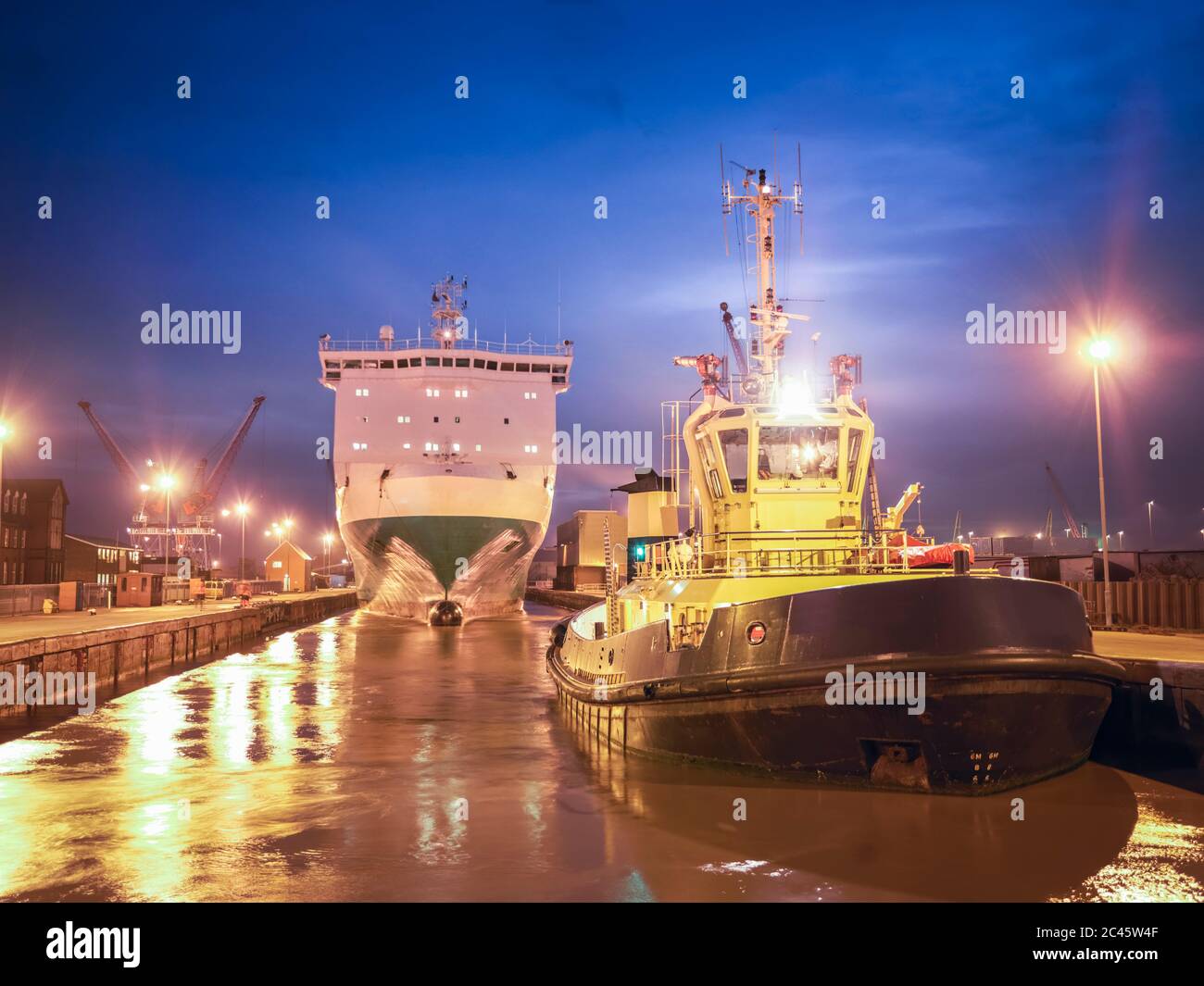 Remolca un bote esperando en el mar para remolcar el ferry desde el puerto al mar por la noche. Foto de stock