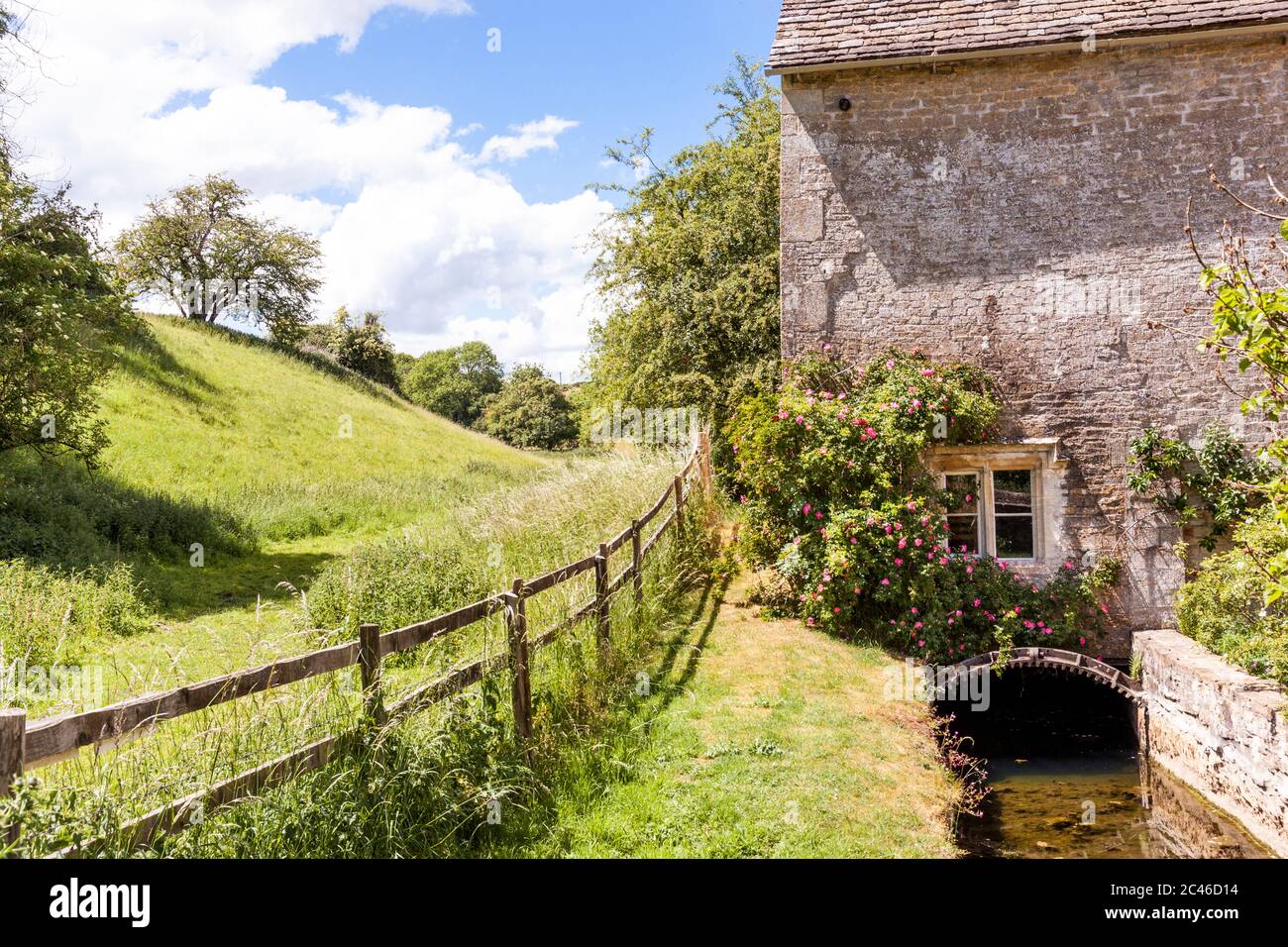 Rosas creciendo sobre el leat molino de Winson Mill en el Valle de Coln en el pueblo de Cotswold de Winson, Gloucestershire Reino Unido Foto de stock