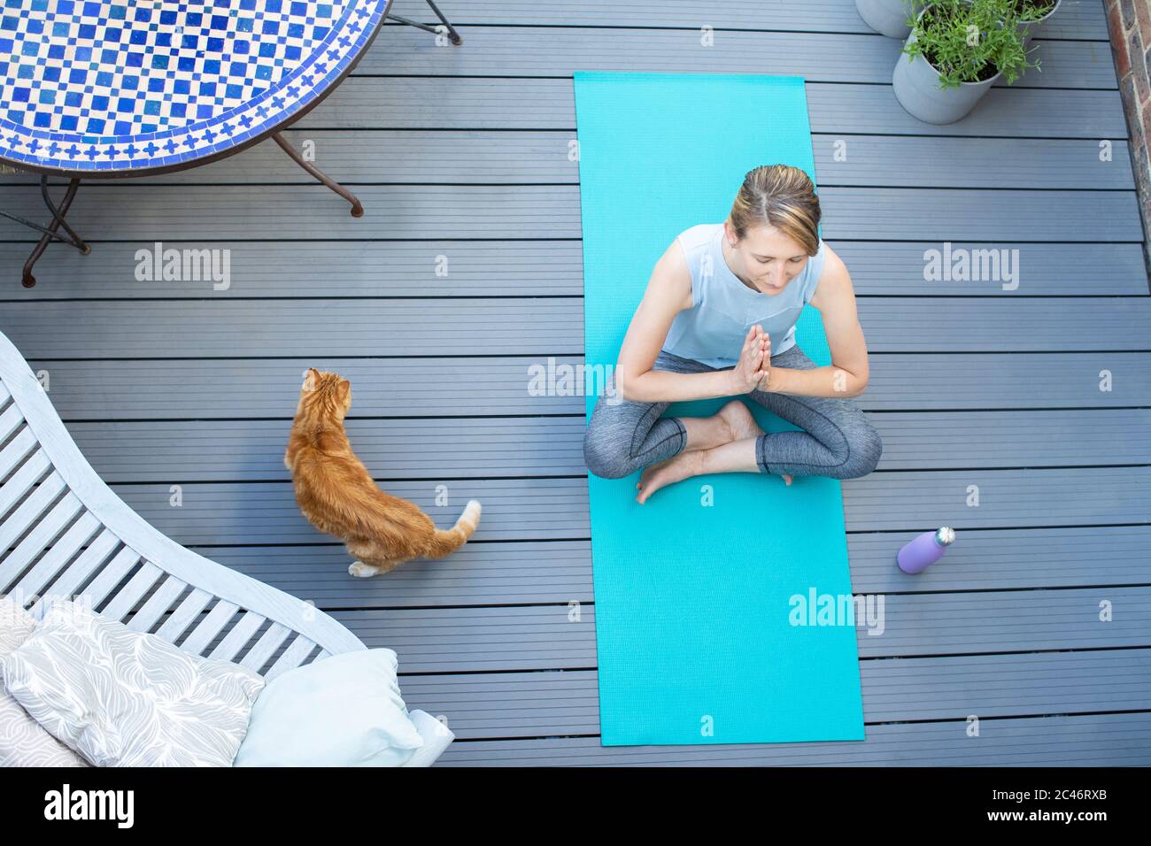 Vista superior de la mujer madura con gato de mascotas en casa meditando con yoga en cubierta Foto de stock