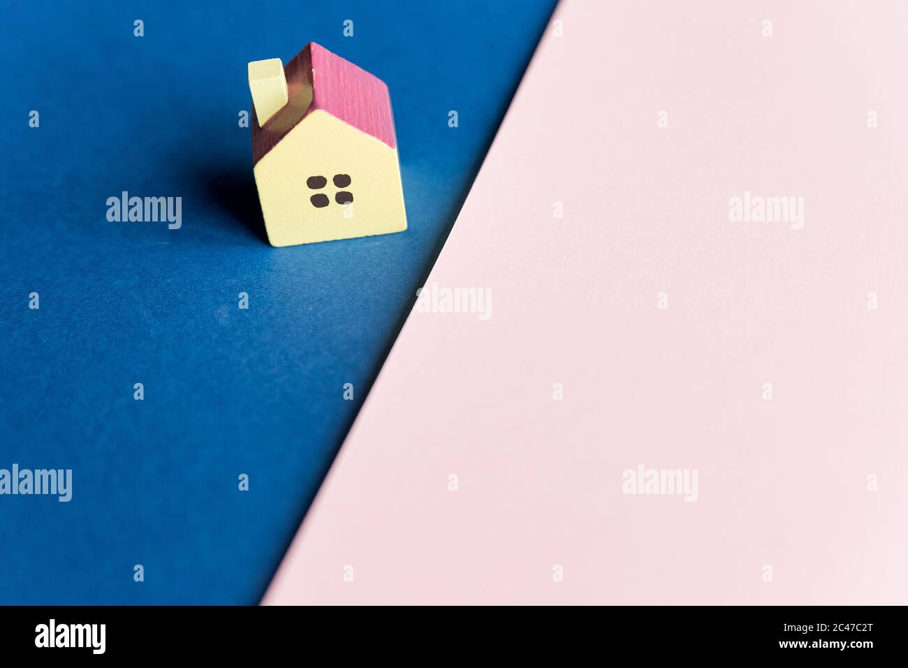 Inmobiliaria, casa modelo al aire libre, closeup.Casa modelo de madera sobre un fondo geométrico rosa y azul con copia space.Concept para la escalera de la propiedad Foto de stock