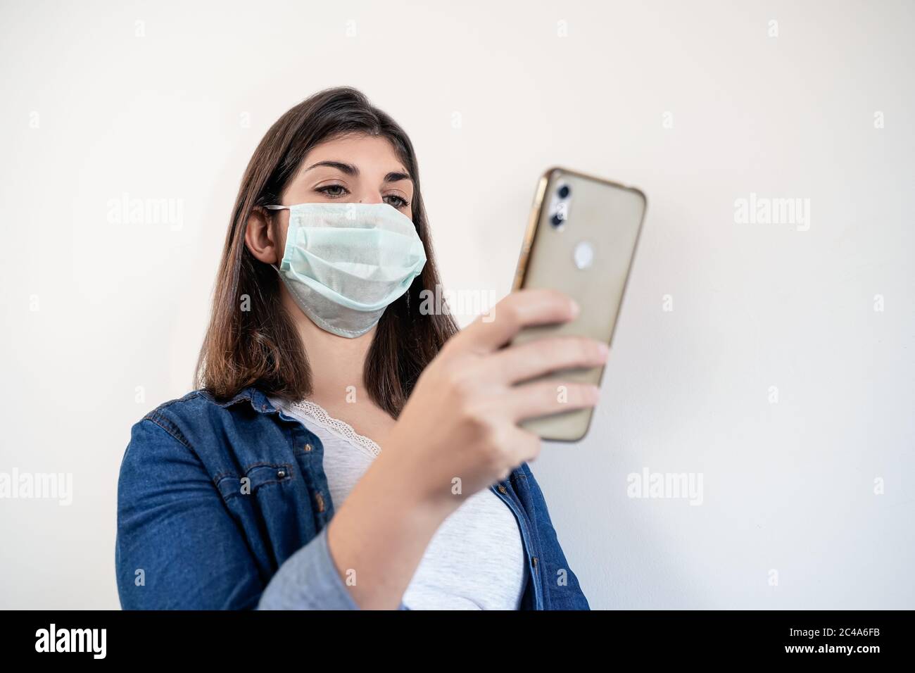 Retrato de mujer con máscara de protección médica utilizando su smartphone. Foto de stock