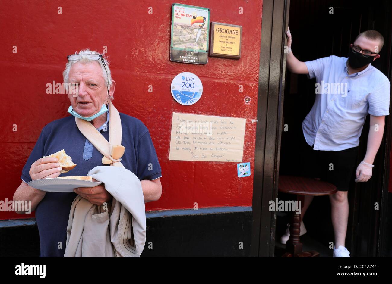 El político irlandés Nicky Kelly come su sándwich tostado gratis que le dio el barman Daniel Smith (derecha) en Grogans Castle Lounge en el centro de la ciudad de Dublín. El pub anunció en las redes sociales que esta tarde iban a repartir gratuitamente algunos de sus amadas tostadas. Los bares de los hoteles y pubs que operan como restaurantes pueden comenzar a reabrir al público el lunes 29 de junio, de conformidad con la fase 3 del Gobierno de flexibilización de las restricciones COVID-19. Foto de stock