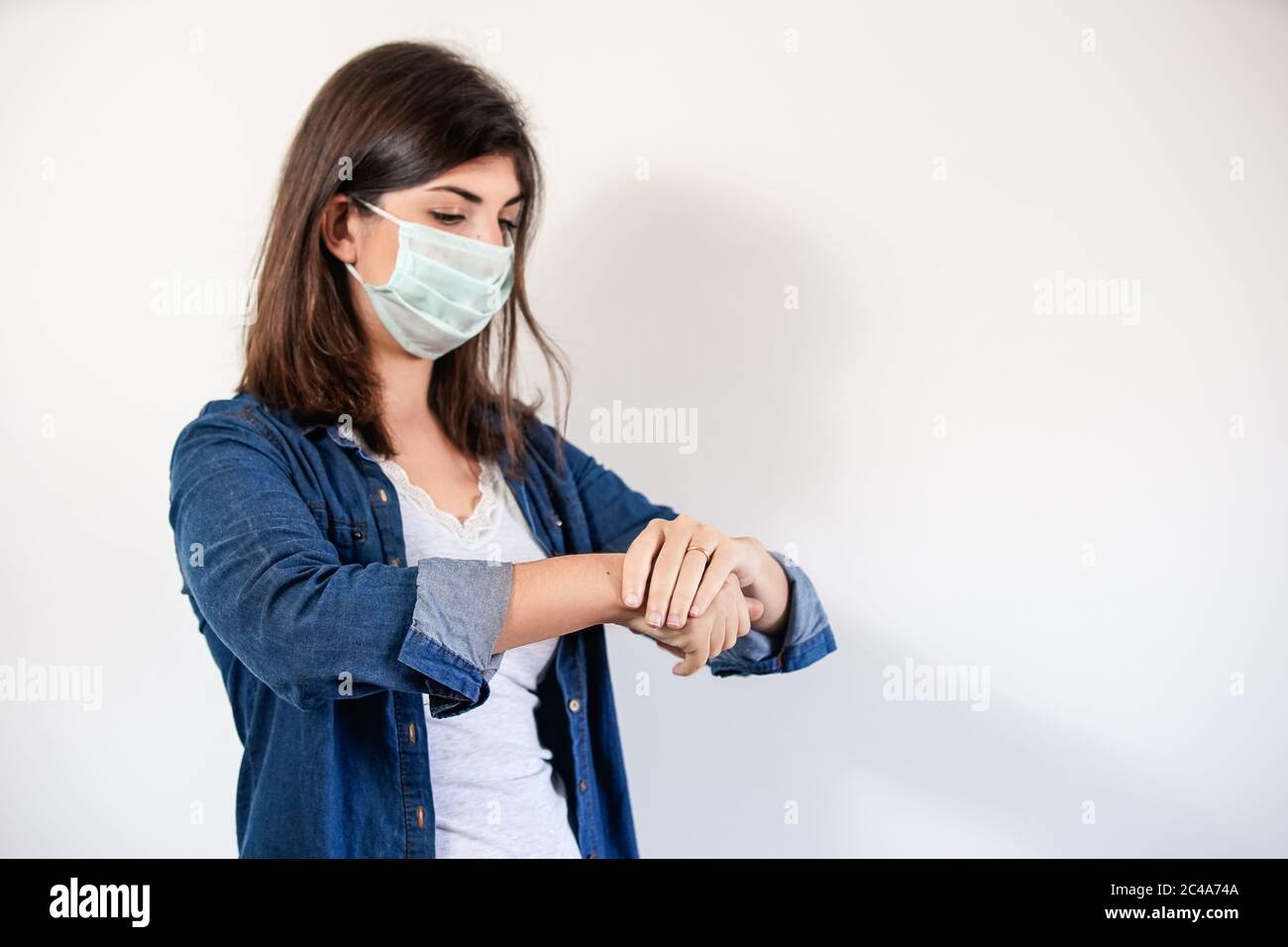 Mujer con máscara de protección médica poniendo antiséptico para desinfectar sus manos Foto de stock