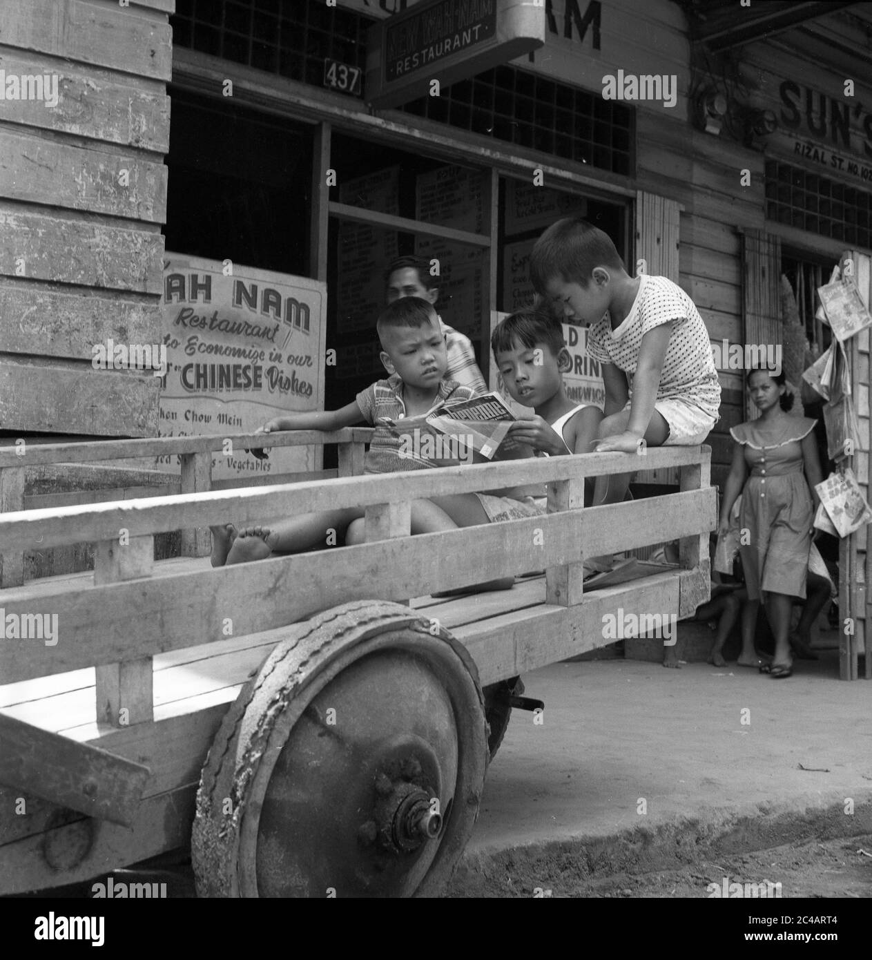 Niños leyendo Cheyenne Comic libro 1959 Street Scene, Filipinas Foto de stock