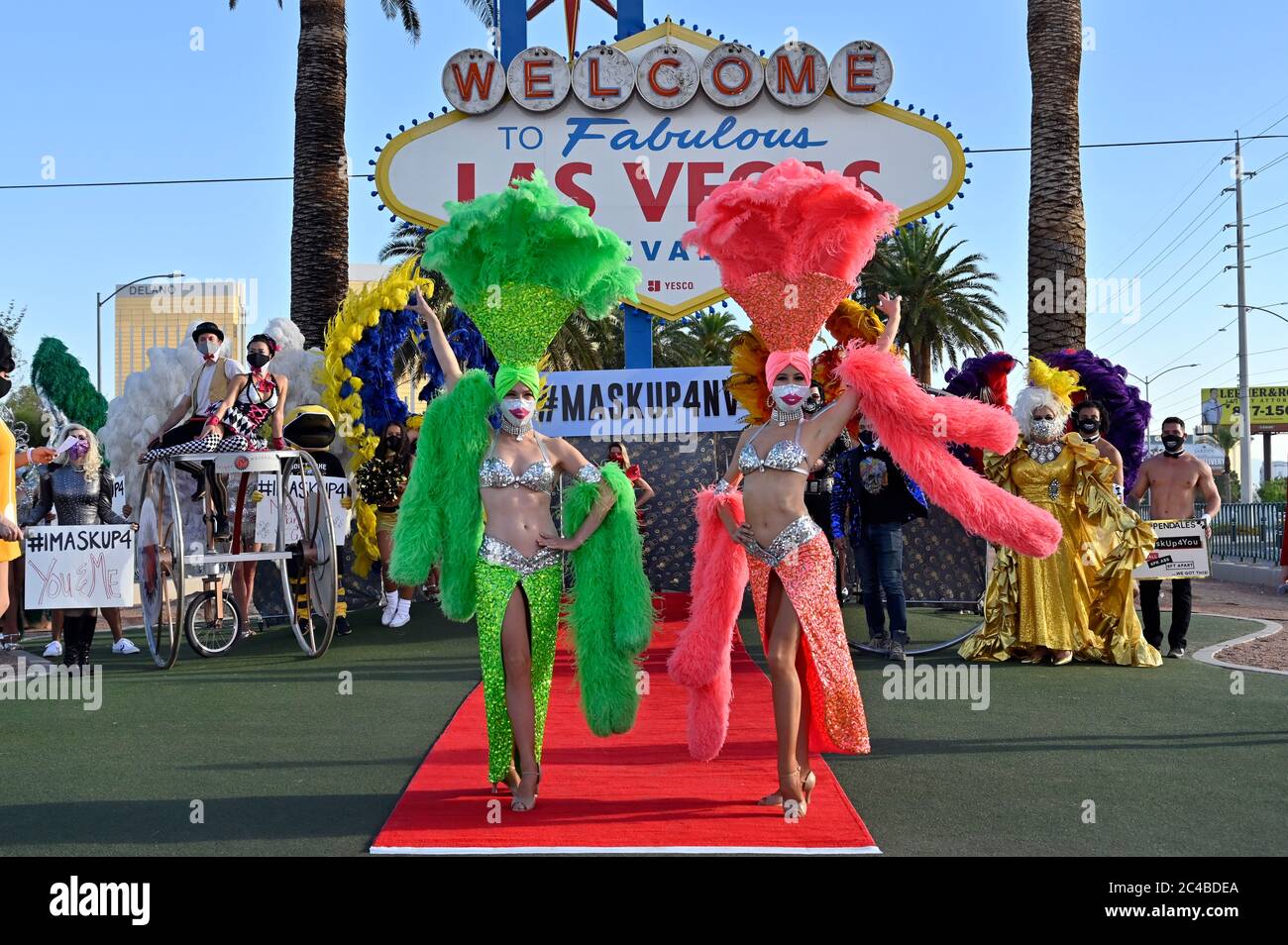 Las Vegas, Nevada, EE.UU. 25 de junio de 2020. Modelos vestidos como  showgirls participa en un desfile de moda frente al cartel de bienvenida a  las Vegas fabuloso en las Vegas Strip