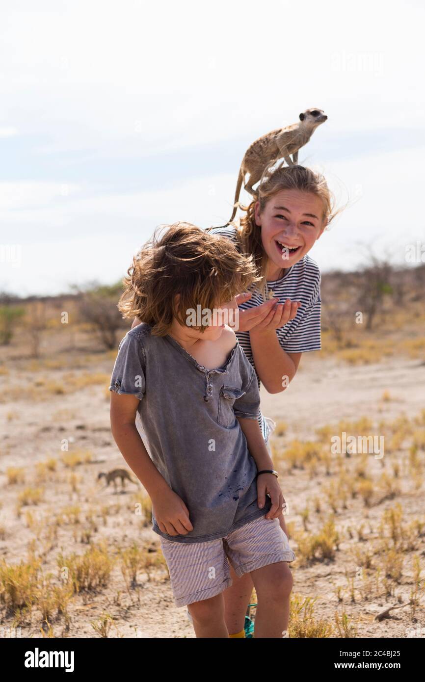 Niño de 5 años con Meerkat en la cabeza, desierto de Kalahari, salar Makgadikgadi, Botswana Foto de stock
