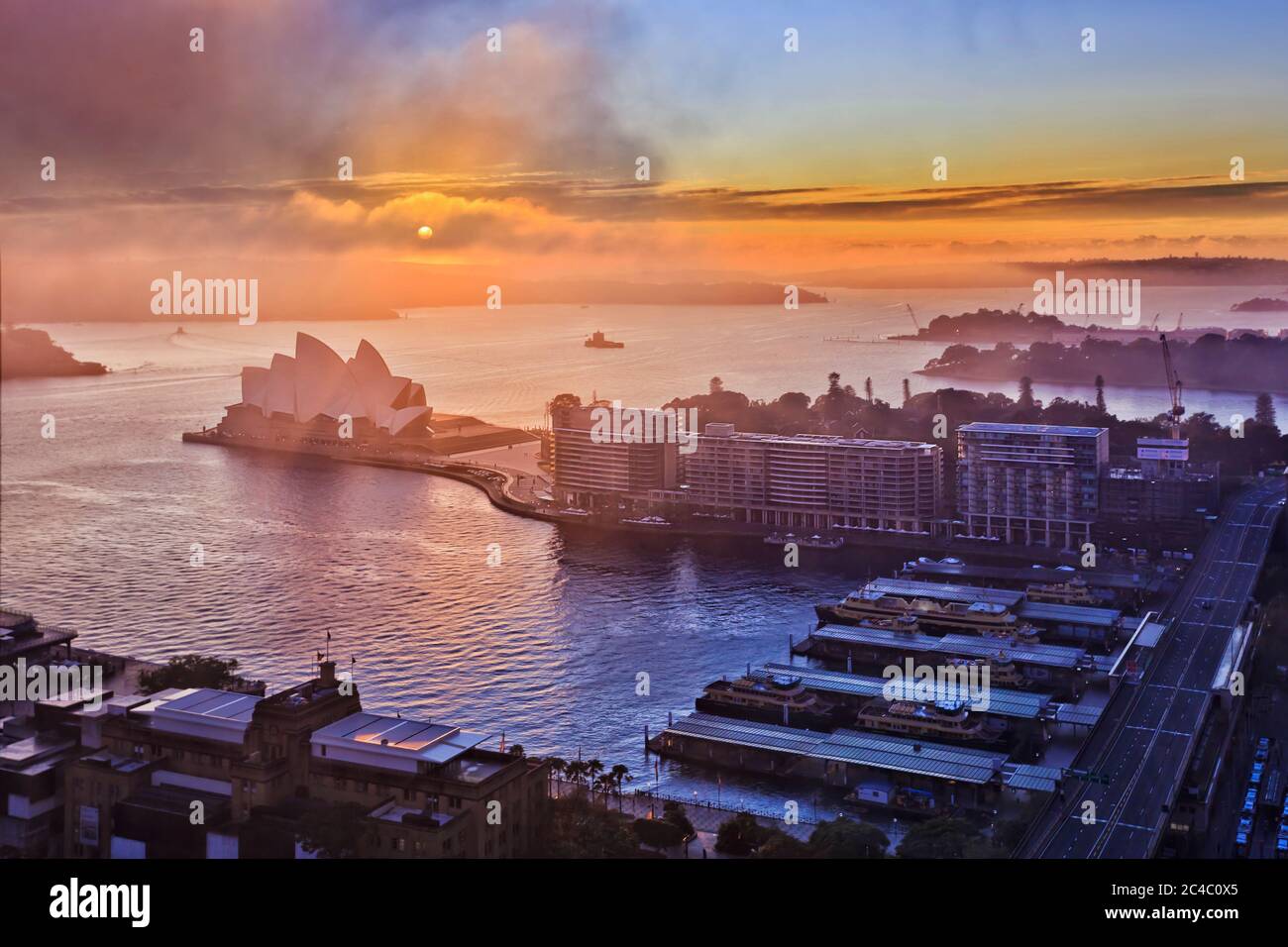 Niebla y nubes al amanecer cubriendo el sol sobre los principales puntos de interés de la ciudad de Sydney, en el muelle Circular Quay del puerto de Sydney. Foto de stock