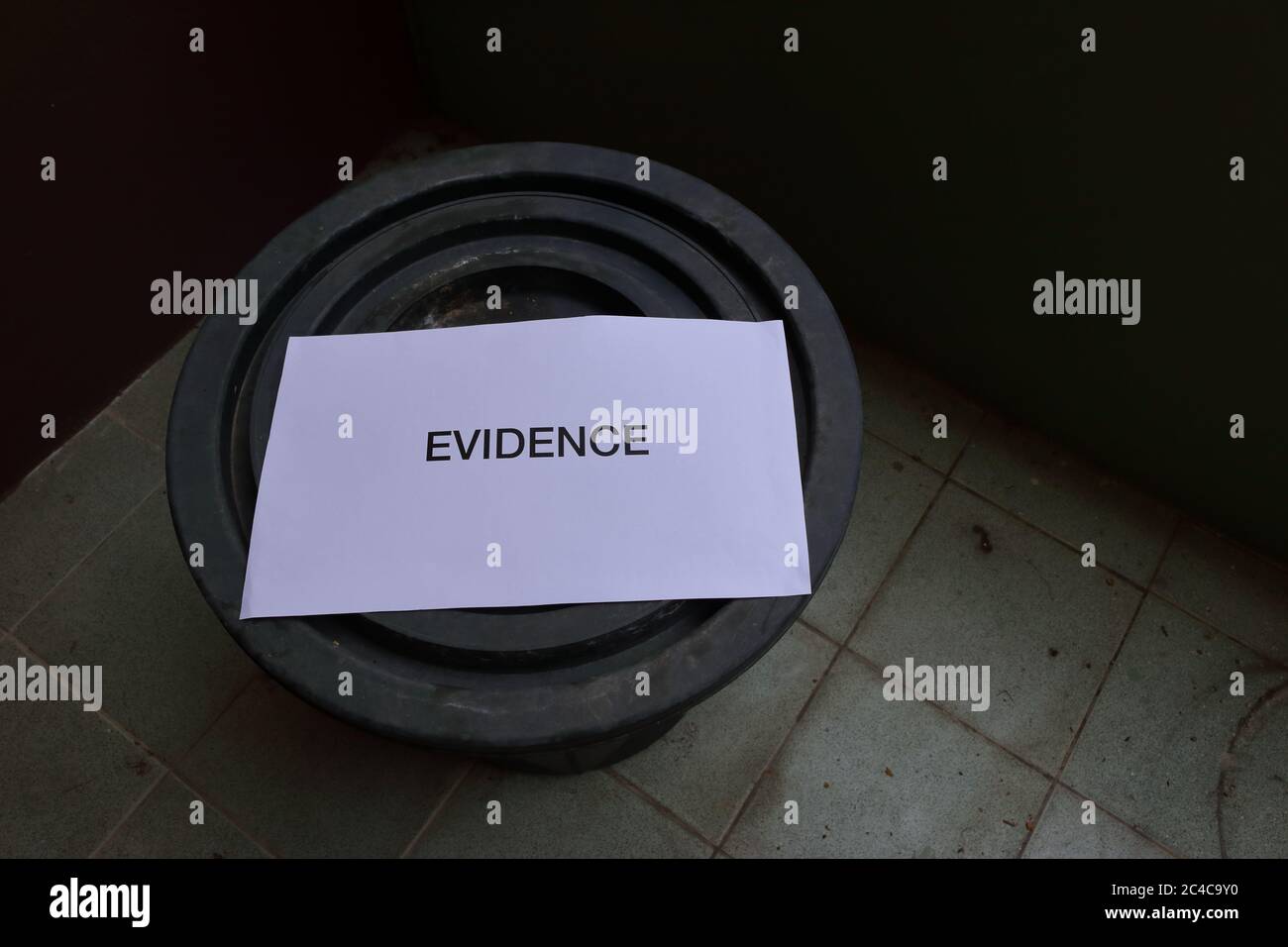 Enfoque selectivo en la evidencia de palabras en el signo de papel colocado en la parte superior de la tapa cerrada cubo negro en el suelo de baldosas, vista de ángulo alto Foto de stock
