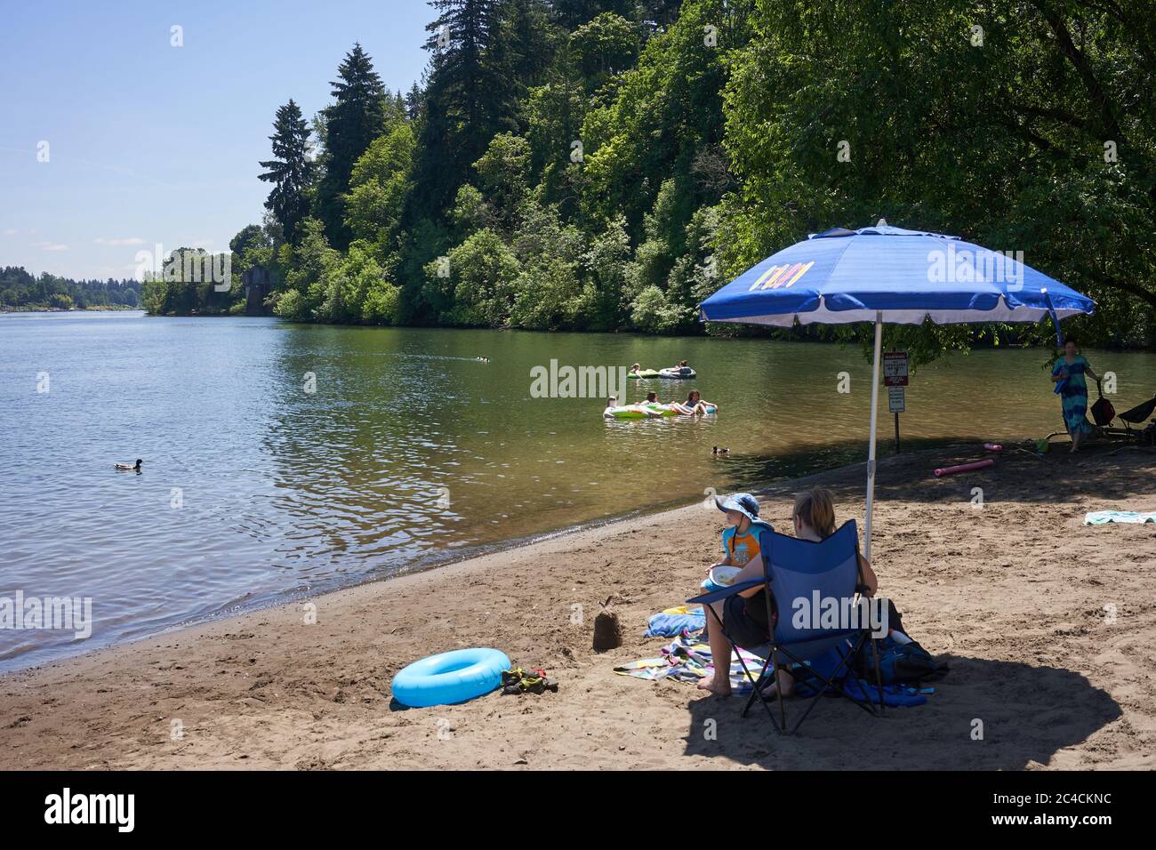Las familias disfrutan del aire libre en la playa del río Willamette en el lago Oswego, Oregón, mientras el verano comienza en medio de la pandemia del coronavirus el 25 de junio de 2020. Foto de stock