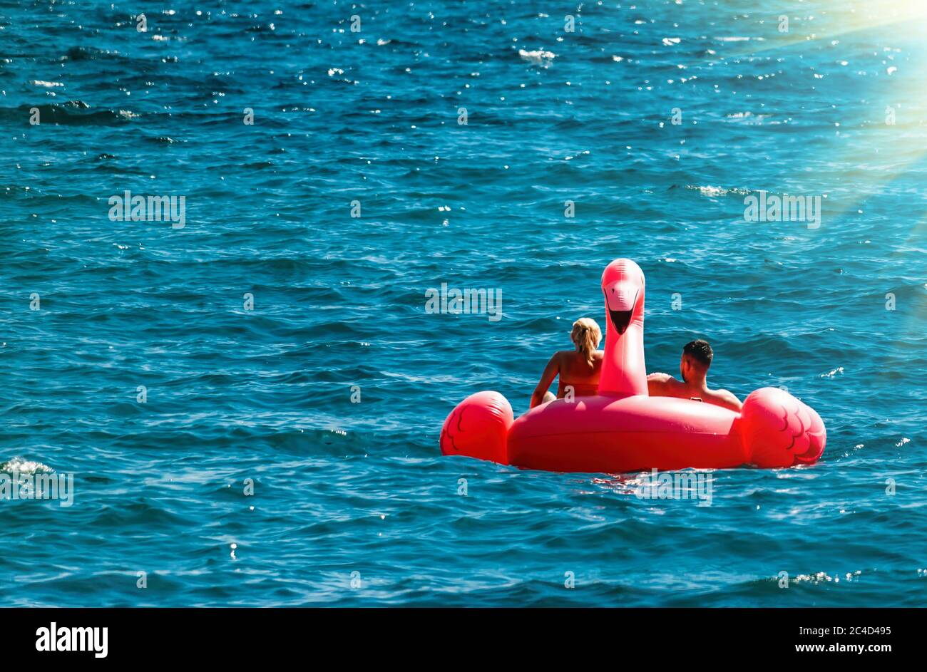 Pareja pasándose en los flamencos rosados en el mar azul. Puesta del sol  vacaciones viajes fondo de vacaciones con divertido juguete flote cabecera  como pareja romántica Fotografía de stock - Alamy