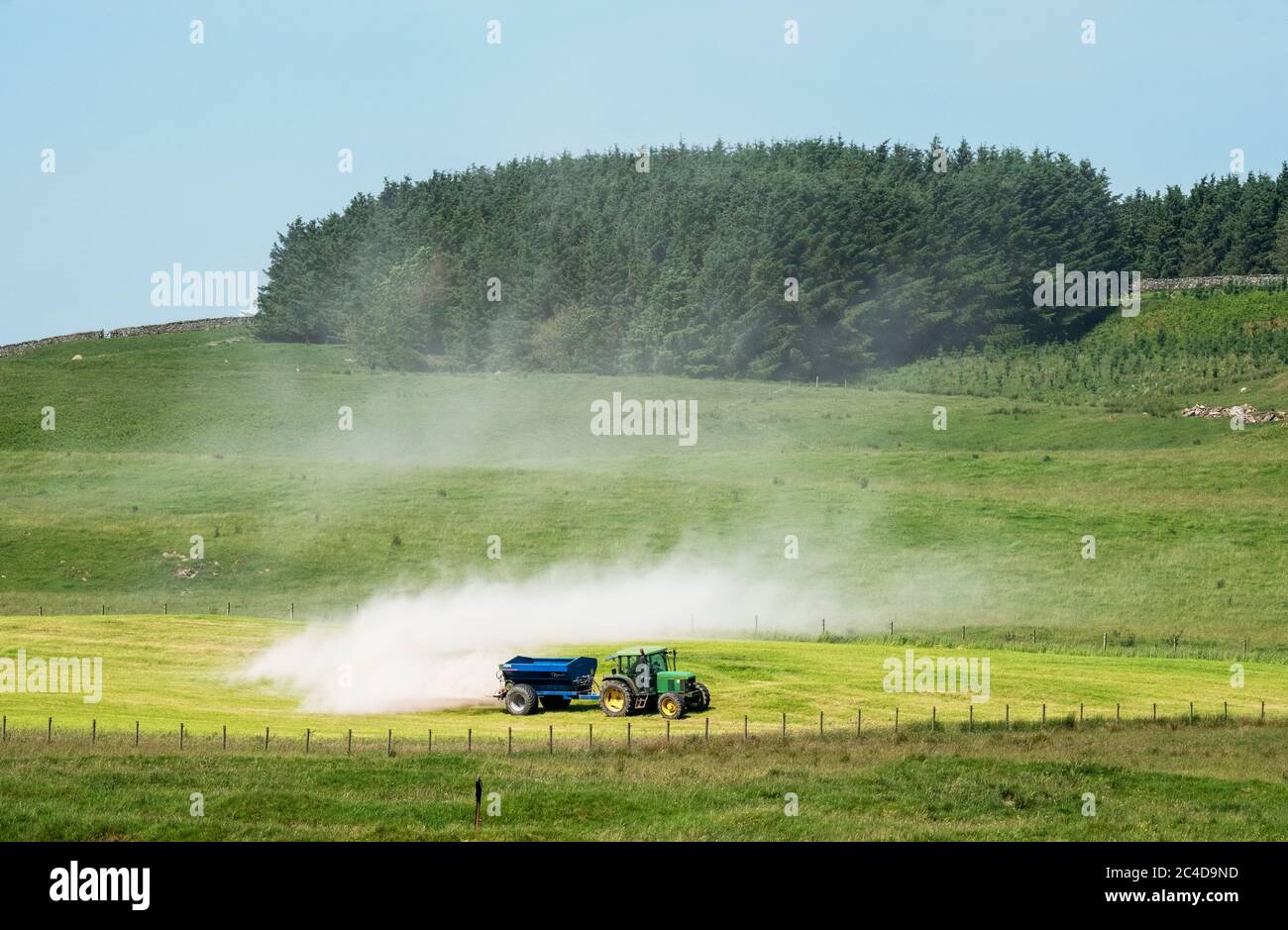 Tractor y remolque que extienden cal en un campo de hierba cerca de Shankend, Hawick, Scottish Borders. Foto de stock
