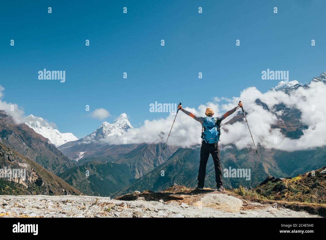 Imagen del concepto de vacaciones activas. Joven excursionista mochilero hombre elevándose brazos con bastones de trekking disfrutando de la montaña Thamserku 6608m durante la altitud Foto de stock