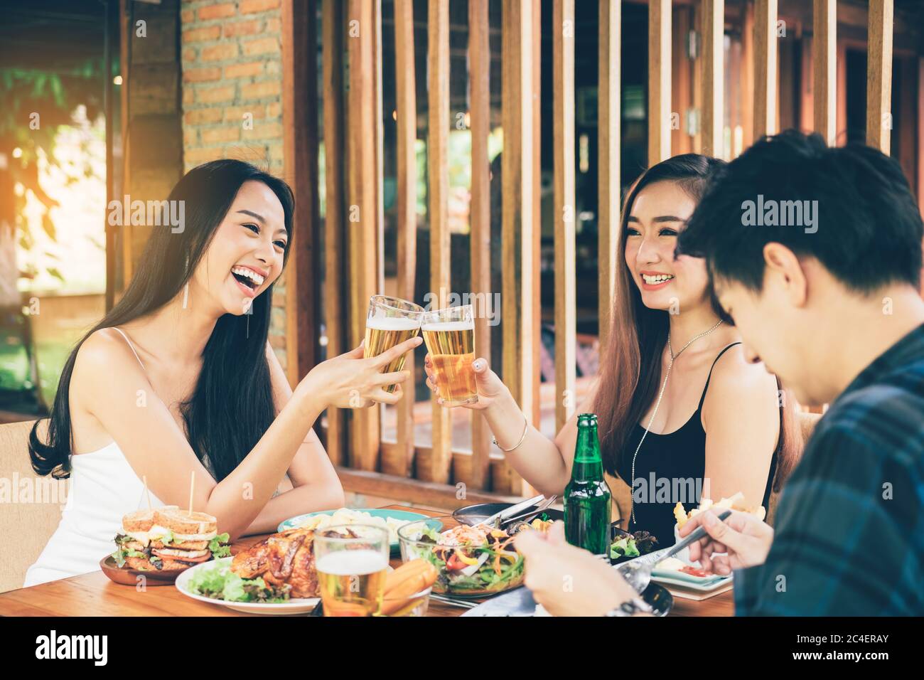 Teeneger amigos asiáticos clinking gafas mientras disfruta de una cena en un restaurante. Foto de stock