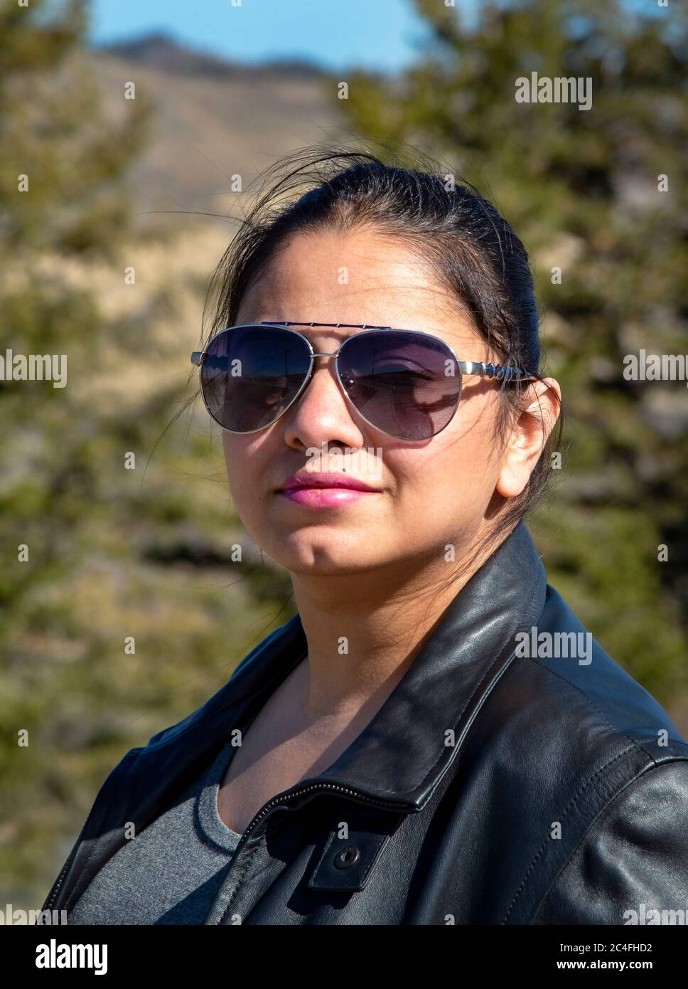 Hermosa mujer joven de pelo oscuro en chaqueta de cuero y gafas de sol Foto de stock