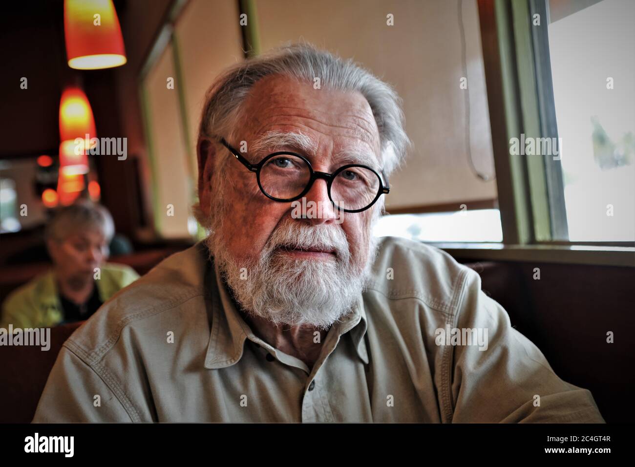 anciano mayor con gafas una barba y preguntas mira al fotógrafo en cara completa y pelo gris Foto de stock