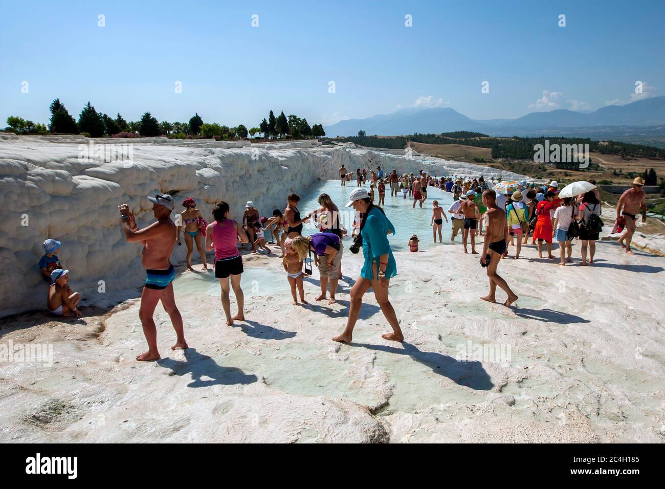 Los turistas se reúnen en la cima de las piscinas termales en los travertinos, o el castillo de algodón, en Pamukkale en Turquía. Foto de stock