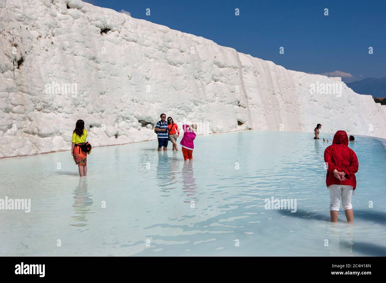 La gente se encuentra en una de las piscinas termales en los travertinos, o el castillo de algodón, en Pamukkale en Turquía. Foto de stock