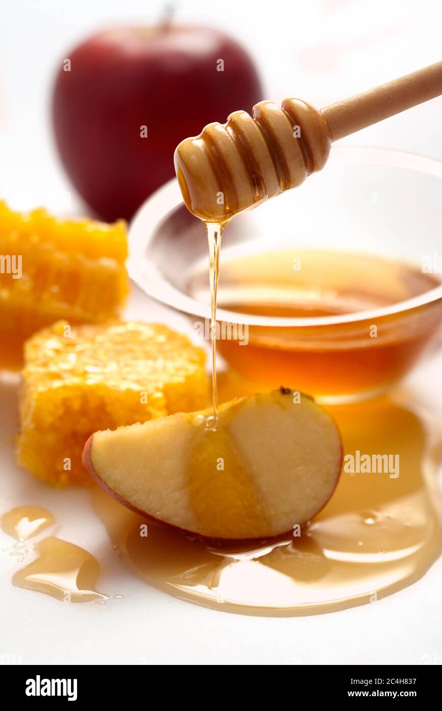 Miel goteando en una manzana. Manzanas y miel con el frasco. Fiesta judía de año nuevo. Aislado sobre blanco. Foto de stock