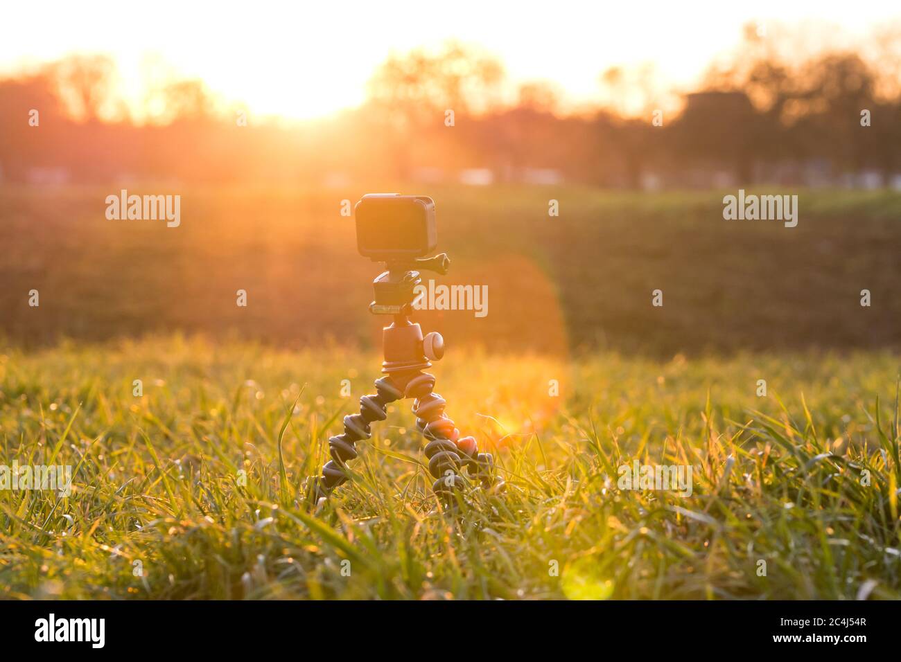 Cámara de acción en un prado de hierba que filmaba hermosa y dramática puesta de sol Foto de stock