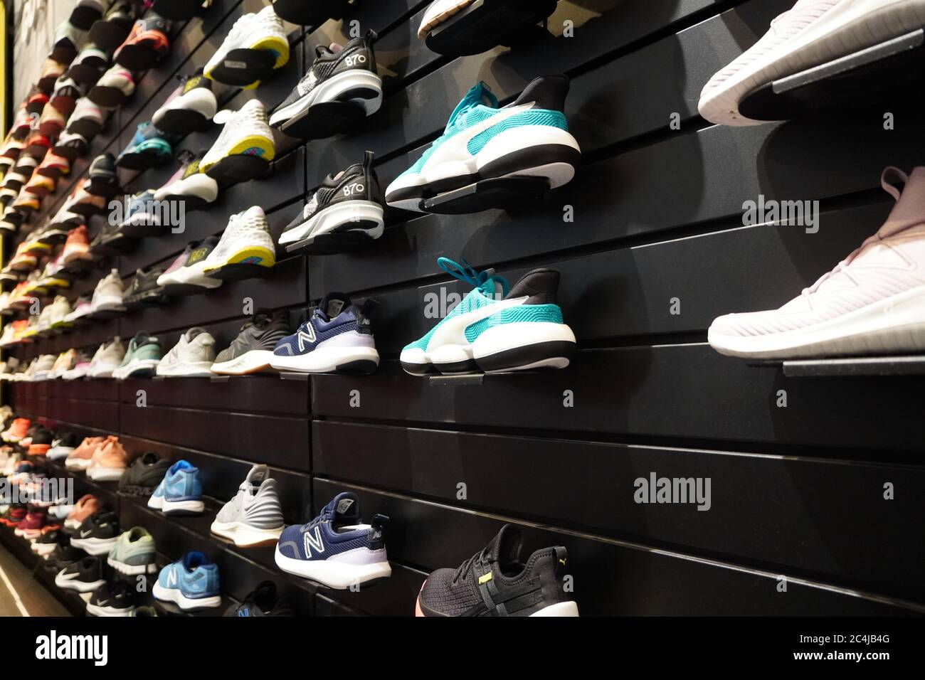 Ver la exhibición de muchos zapatos deportivos en una pared. Una de una pared de zapatos dentro de la tienda. Nuevas y modernas zapatillas de running con estilo para hombre y