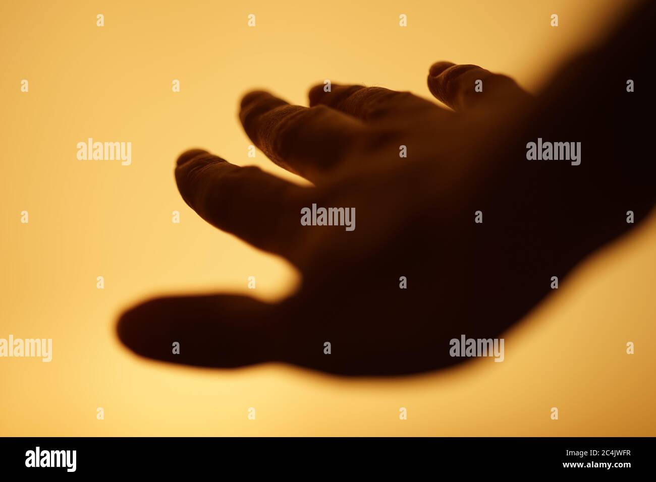 la mano humana oscura está volando en un espacio amarillo cálido Foto de stock