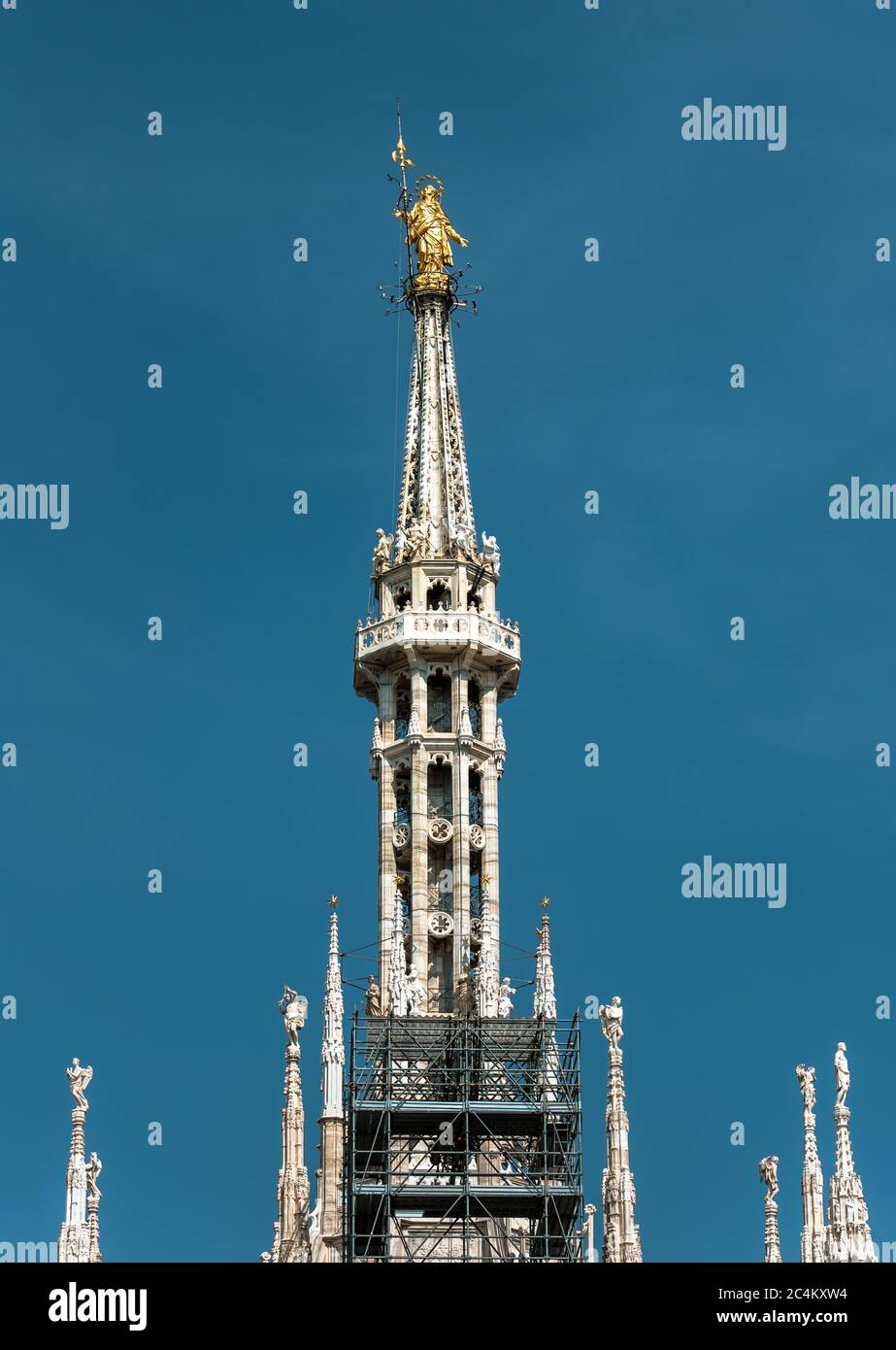 Madonnina en la cima de la Catedral de Milán a la altura de 108.5 m en Milán, Italia. Estatua de oro de Madonna en la aguja sobre el fondo azul del cielo. Famoso Milán ca Foto de stock