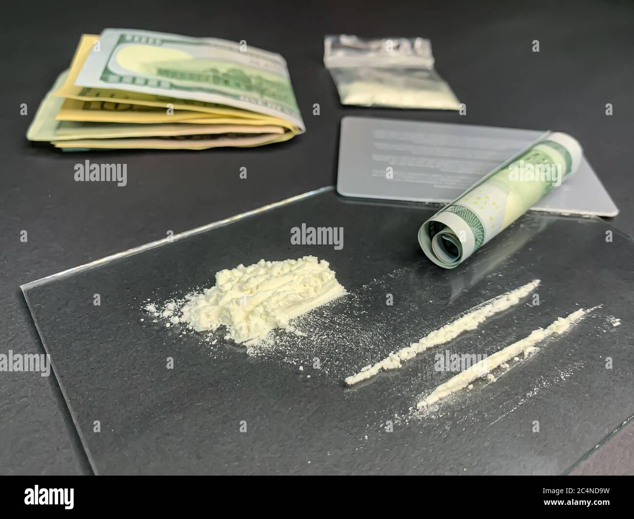 Rodó 100 dólares, 2 líneas de cocaína, bolsa de plástico con drogas  ilegales y tarjetas de crédito sobre un fondo gris. Adicción a las drogas.  Imagen de stock Fotografía de stock - Alamy