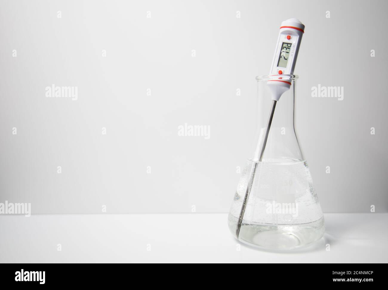 Termómetro digital que mide la temperatura de un líquido en un matraz  erlenmeyer de vidrio sobre fondo blanco. Experimento científico Fotografía  de stock - Alamy